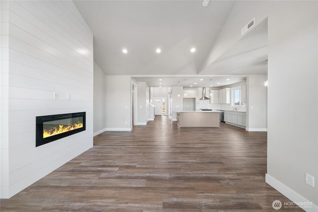 unfurnished living room featuring visible vents, a fireplace, baseboards, dark wood-type flooring, and vaulted ceiling
