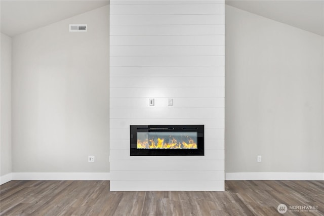 details with baseboards, visible vents, wood finished floors, and a fireplace