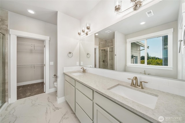 full bath with a spacious closet, a shower stall, a sink, and marble finish floor