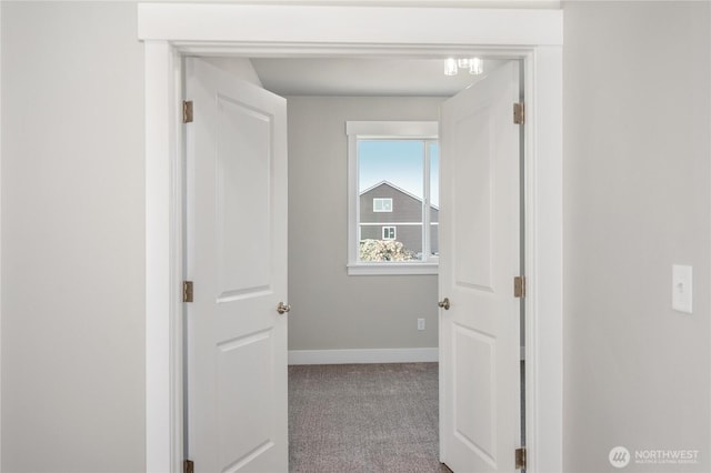 corridor with baseboards and carpet flooring