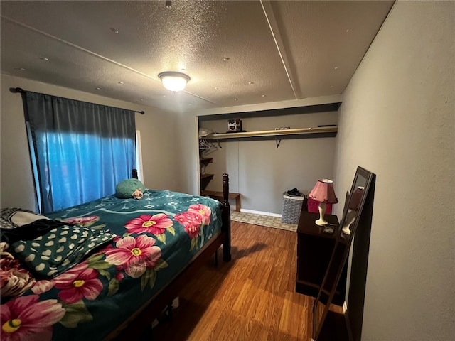 bedroom with a textured ceiling and wood finished floors