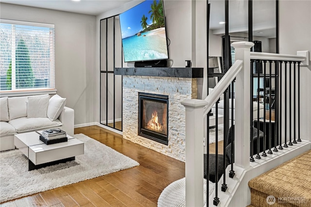 living room with baseboards, stairs, wood finished floors, and a fireplace