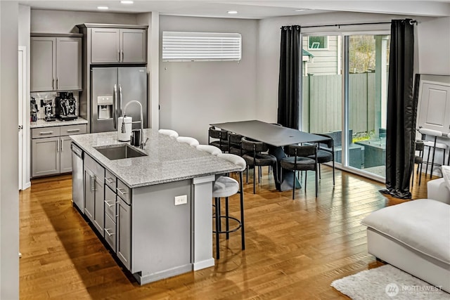kitchen featuring a sink, a kitchen breakfast bar, gray cabinets, stainless steel appliances, and recessed lighting