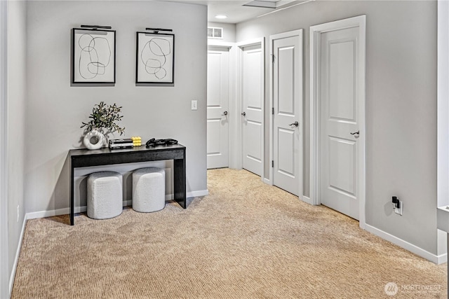 hall with carpet floors, baseboards, and visible vents