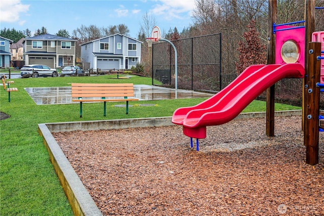communal playground with fence, a yard, and a residential view