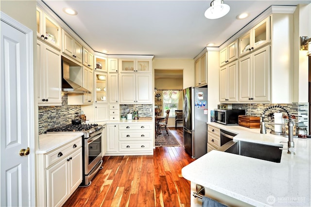 1664 Shine Rd, Port Ludlow, WA 98365 - kitchen featuring stainless steel appliances, wall chimney exhaust hood, dark wood finished floors, decorative backsplash, and recessed lighting