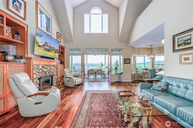 1664 Shine Rd, Port Ludlow, WA 98365 - living area featuring wood finished floors, high vaulted ceiling, a fireplace, and a chandelier