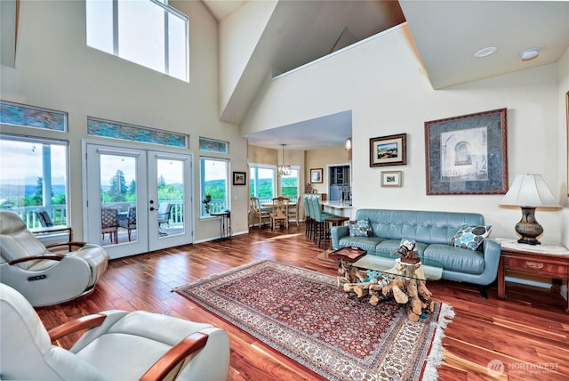 1664 Shine Rd, Port Ludlow, WA 98365 - living room featuring wood finished floors, french doors, a chandelier, and a high ceiling