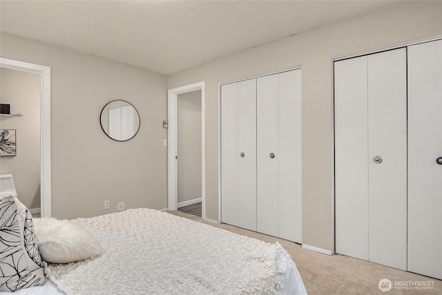 bedroom with baseboards, multiple closets, and carpet