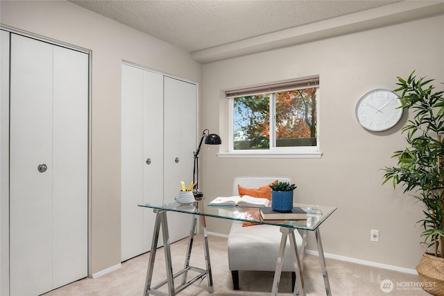 office featuring a textured ceiling, light carpet, and baseboards