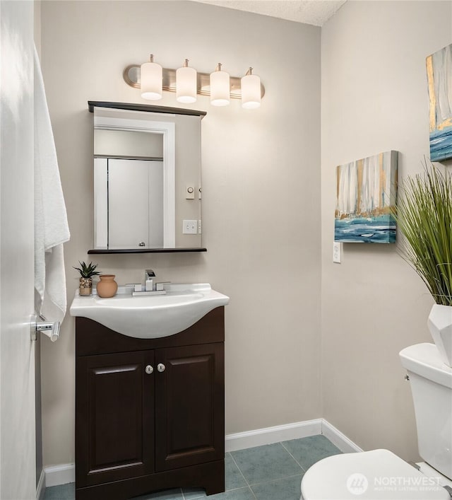 bathroom with vanity, baseboards, tile patterned floors, and toilet