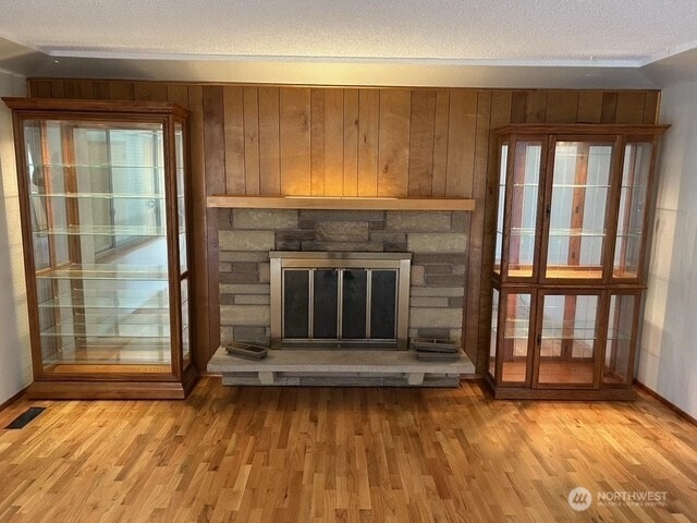 unfurnished living room with light wood-type flooring, visible vents, a fireplace, and a healthy amount of sunlight