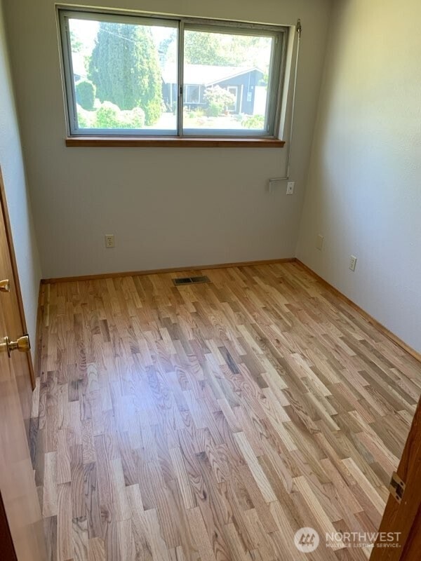unfurnished room with light wood finished floors, visible vents, and baseboards