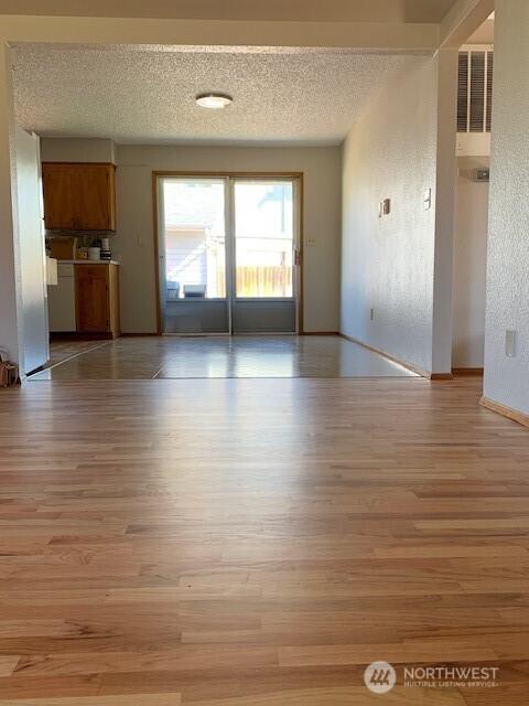 501 S 88th St, Tacoma, WA 98408 - unfurnished living room with baseboards, light wood finished floors, and a textured ceiling