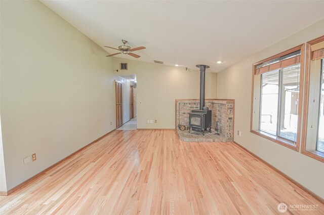 4310 Brookdale Rd E, Tacoma, WA 98446 - unfurnished living room featuring a wood stove, wood finished floors, a ceiling fan, and baseboards
