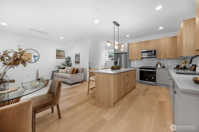kitchen with a sink, a center island, stainless steel appliances, and light wood-type flooring