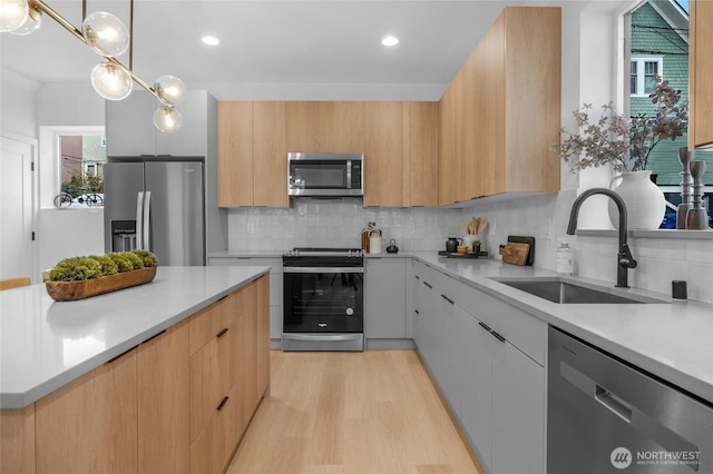 kitchen featuring light countertops, stainless steel appliances, a sink, and modern cabinets