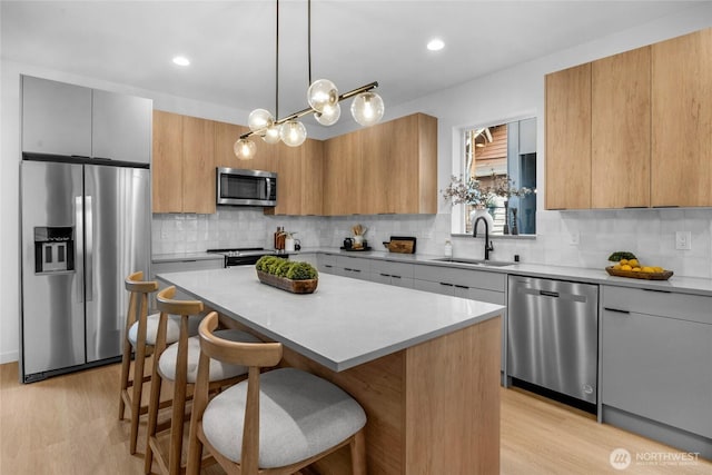 kitchen featuring a sink, a breakfast bar area, a center island, stainless steel appliances, and backsplash