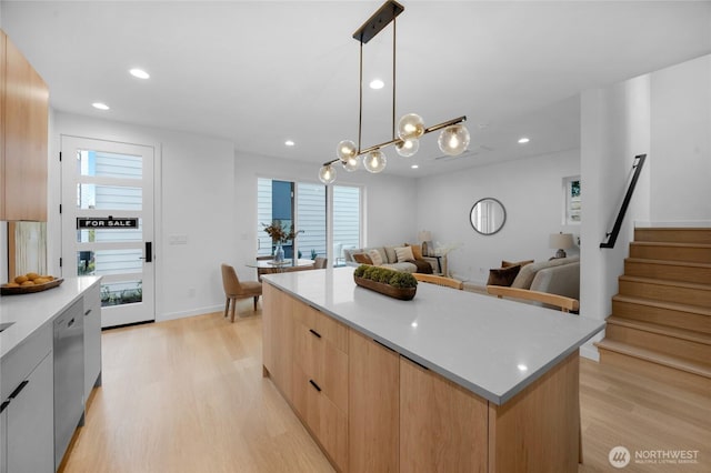 kitchen with light wood-style floors, light countertops, a kitchen island, stainless steel dishwasher, and modern cabinets