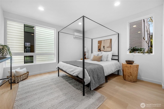 bedroom with baseboards, recessed lighting, wood finished floors, and an AC wall unit