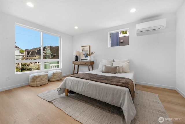 bedroom with baseboards, a wall unit AC, recessed lighting, and wood finished floors