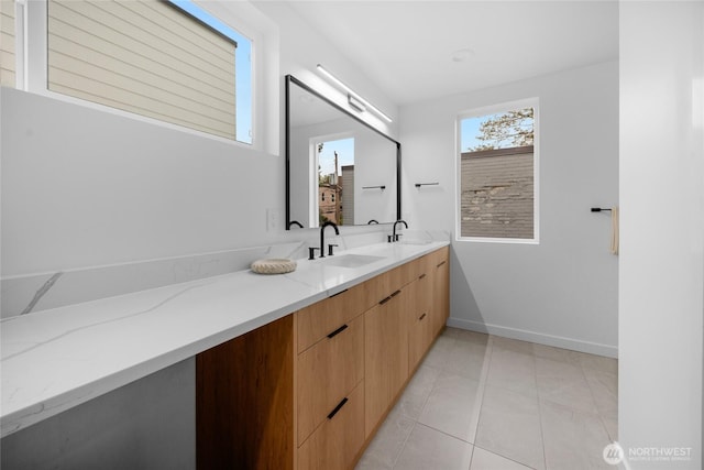 bathroom with double vanity, baseboards, a sink, and tile patterned flooring