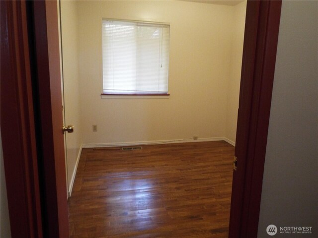 spare room with baseboards and wood finished floors