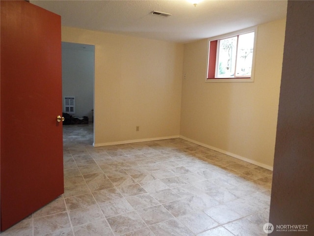 unfurnished room featuring baseboards and heating unit