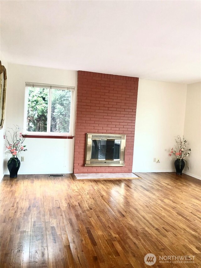 unfurnished living room with wood finished floors, a fireplace, and baseboards