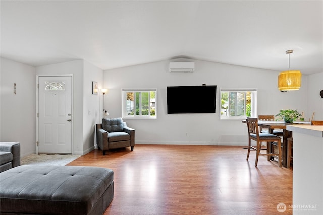 living room featuring an AC wall unit, baseboards, vaulted ceiling, and light wood-style flooring
