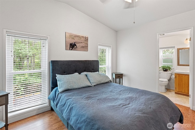 bedroom with light wood-style floors, multiple windows, and vaulted ceiling