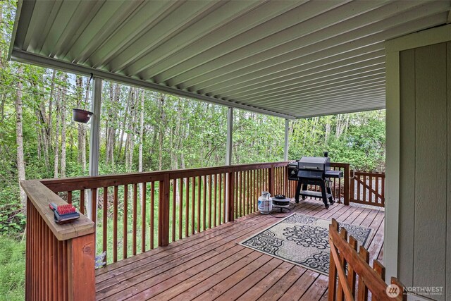 wooden terrace featuring grilling area and a wooded view