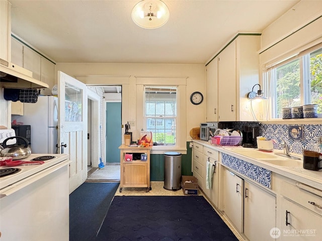 kitchen with white appliances, light countertops, plenty of natural light, and white cabinets