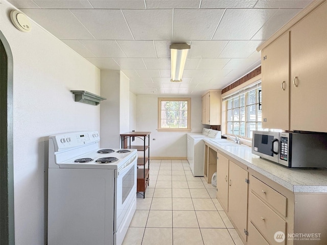 kitchen with white range with electric stovetop, stainless steel microwave, washer / clothes dryer, a sink, and light countertops