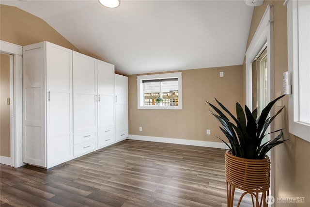 unfurnished room featuring baseboards, dark wood finished floors, and lofted ceiling