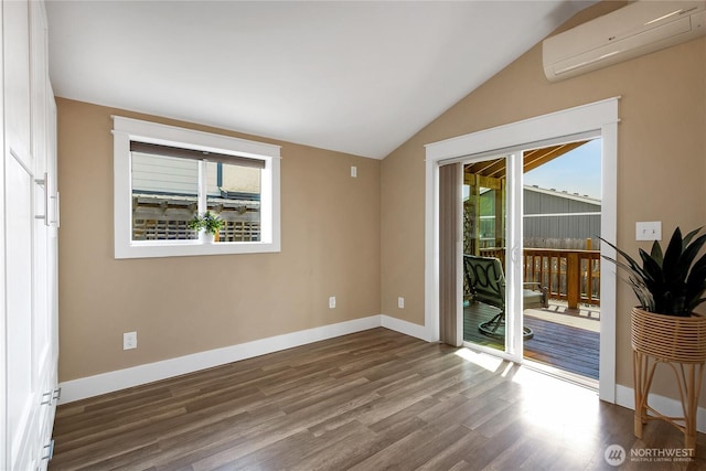 unfurnished room featuring wood finished floors, baseboards, a wall mounted AC, and vaulted ceiling
