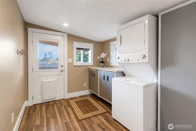 laundry area with baseboards, stacked washing maching and dryer, dark wood-style floors, recessed lighting, and cabinet space