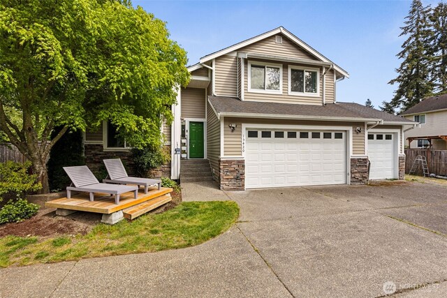 craftsman-style home featuring fence, concrete driveway, an attached garage, a shingled roof, and stone siding