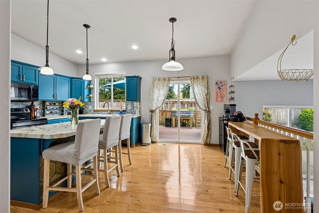 kitchen with light countertops, appliances with stainless steel finishes, a kitchen bar, and blue cabinets