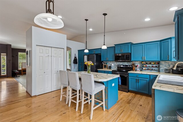 kitchen featuring a sink, blue cabinetry, backsplash, and stainless steel appliances