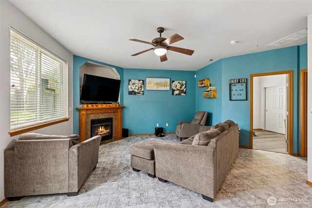 living room with baseboards, a fireplace, a ceiling fan, and visible vents