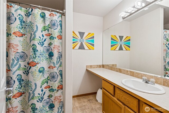full bath featuring baseboards, curtained shower, and vanity