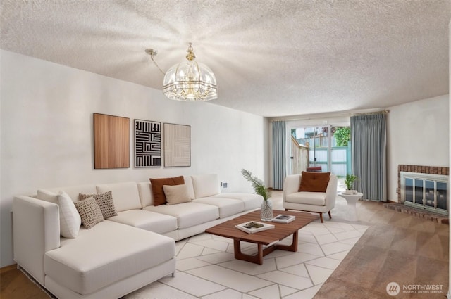living area featuring a brick fireplace, a textured ceiling, and a chandelier