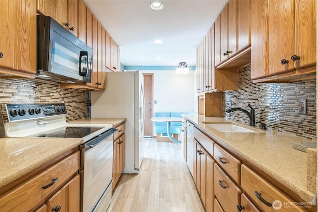 kitchen with decorative backsplash, electric range, black microwave, a sink, and light wood-style floors