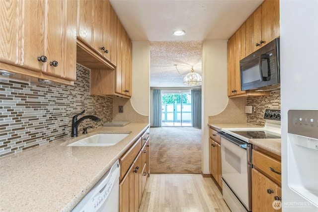 kitchen with light carpet, a sink, white appliances, light wood-style flooring, and decorative backsplash