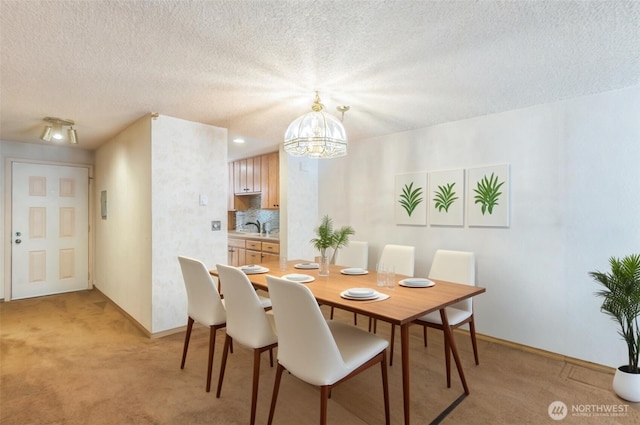 dining space with an inviting chandelier, baseboards, a textured ceiling, and light colored carpet