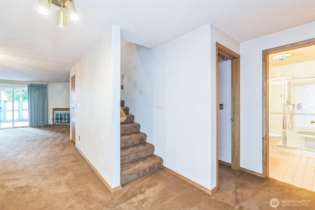 stairway featuring baseboards, a textured ceiling, and carpet