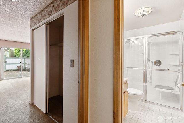 full bathroom with a textured ceiling, toilet, and a shower stall
