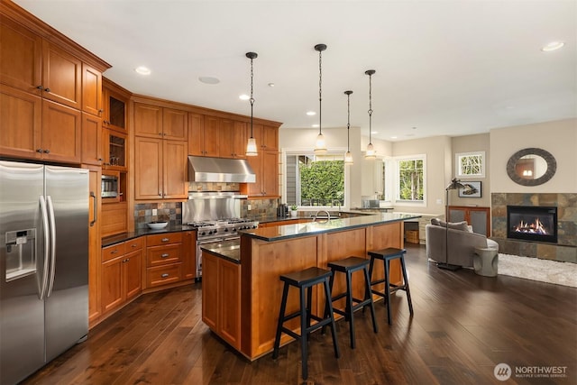 24270 SE 147th Pl, Issaquah, WA 98027 - kitchen with stainless steel appliances, under cabinet range hood, brown cabinetry, open floor plan, and recessed lighting