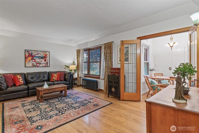 living room with radiator, light wood-style flooring, and baseboards